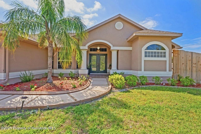 view of front of home with stucco siding, fence, french doors, and a front yard