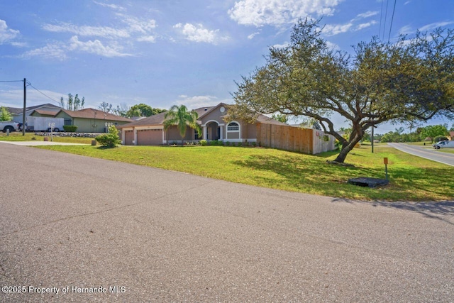 view of front of property with an attached garage, fence, concrete driveway, and a front yard