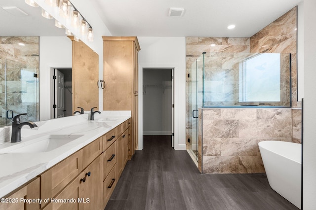 16043 Penn State Rd, Weeki Wachee, FL 34614 - bathroom featuring a stall shower, double vanity, wood finished floors, and a freestanding tub
