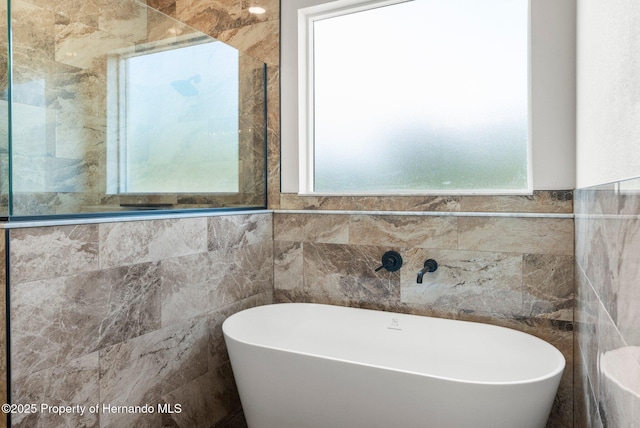 16043 Penn State Rd, Weeki Wachee, FL 34614 - bathroom featuring tile walls and a freestanding bath