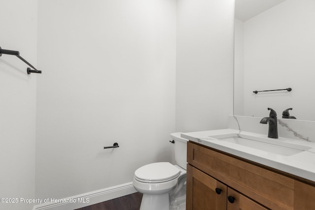 16043 Penn State Rd, Weeki Wachee, FL 34614 - half bathroom with vanity, toilet, baseboards, and wood finished floors