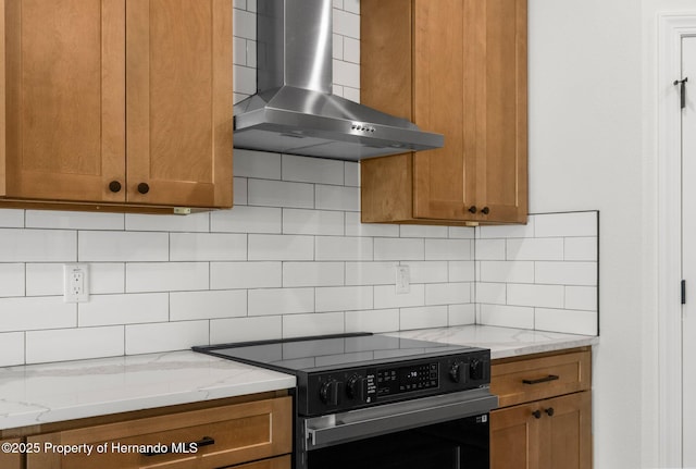 16043 Penn State Rd, Weeki Wachee, FL 34614 - kitchen featuring wall chimney range hood, electric range, brown cabinetry, and backsplash