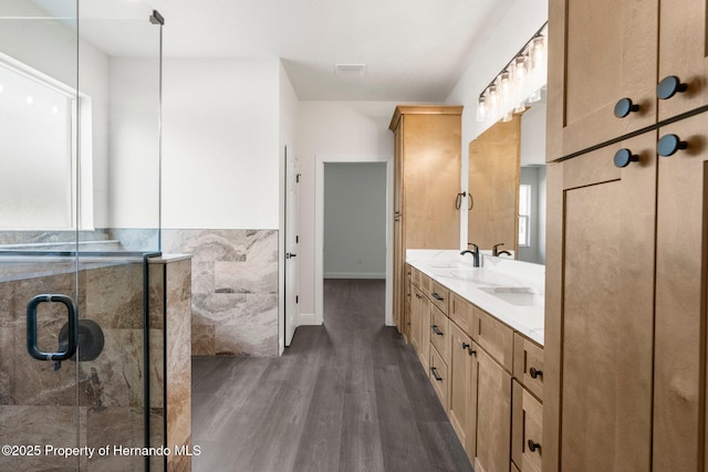 16043 Penn State Rd, Weeki Wachee, FL 34614 - bathroom featuring wood finished floors, double vanity, healthy amount of natural light, and a shower stall