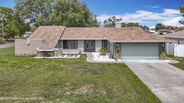 view of front of property with fence, a front lawn, an attached garage, a chimney, and concrete driveway