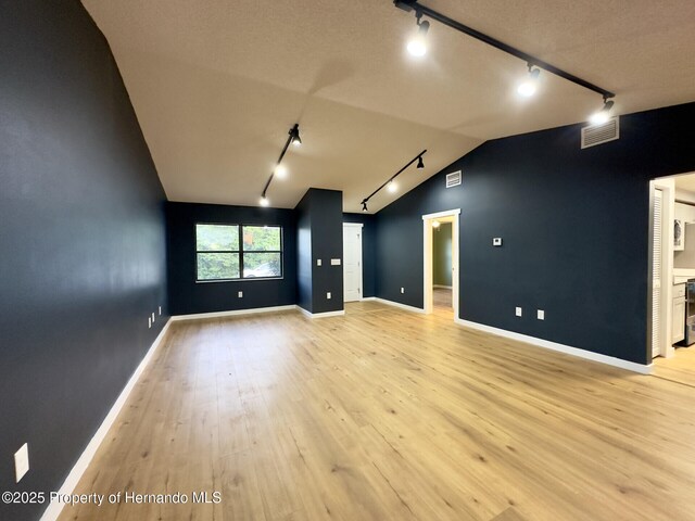 2253 Estill Ave, Spring Hill, FL 34609 - spare room with rail lighting, light wood-style floors, vaulted ceiling, and baseboards