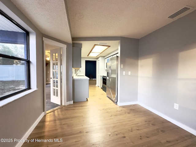 2253 Estill Ave, Spring Hill, FL 34609 - hallway featuring a textured ceiling, light wood-style floors, baseboards, and healthy amount of natural light