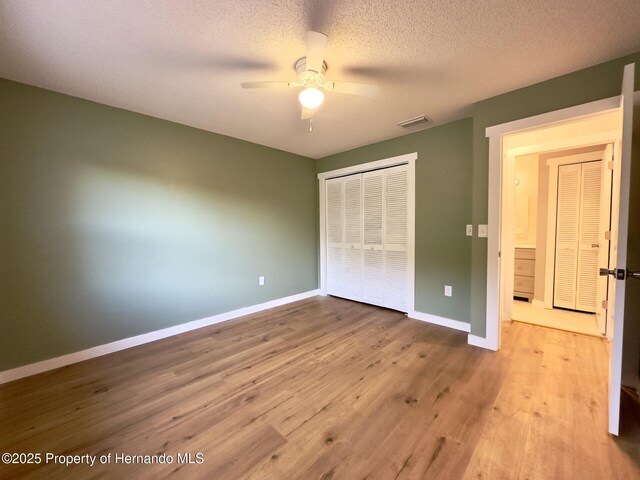 2253 Estill Ave, Spring Hill, FL 34609 - unfurnished bedroom featuring a closet, wood finished floors, baseboards, ceiling fan, and a textured ceiling