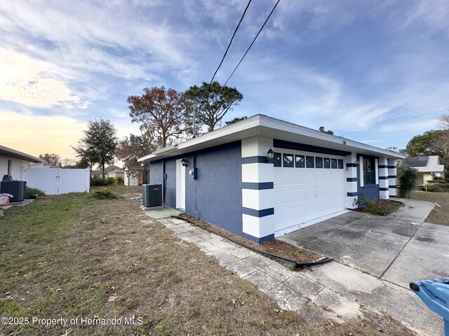 2253 Estill Ave, Spring Hill, FL 34609 - view of home's exterior with cooling unit, an attached garage, concrete driveway, and stucco siding