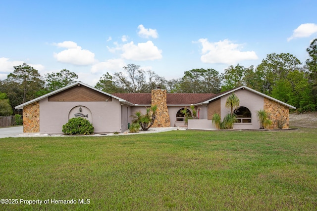 18216 Monteverde Dr, Shady Hills, FL 34610 - view of front of property featuring a chimney, a front yard, and stucco siding