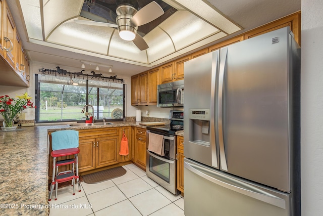 18216 Monteverde Dr, Shady Hills, FL 34610 - kitchen featuring light tile patterned floors, a sink, stainless steel appliances, and brown cabinetry