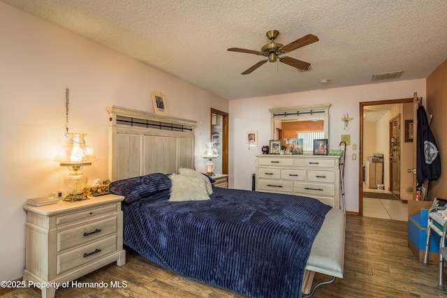 18216 Monteverde Dr, Shady Hills, FL 34610 - bedroom with dark wood-type flooring, a textured ceiling, visible vents, and a ceiling fan