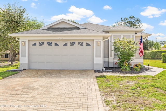 view of front of home featuring stucco siding, decorative driveway, and an attached garage