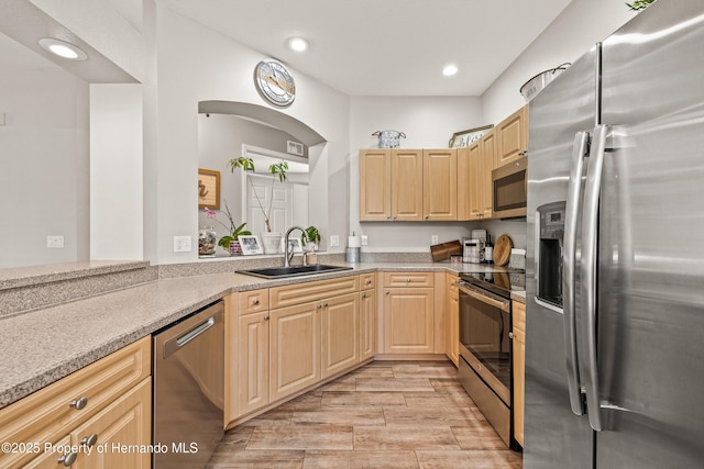 kitchen with stainless steel appliances, wood finish floors, a sink, and light brown cabinetry
