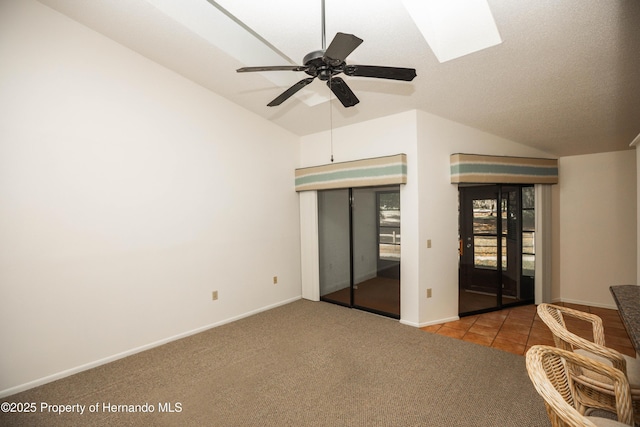 unfurnished bedroom with carpet flooring, baseboards, a ceiling fan, and lofted ceiling with skylight