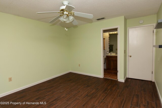 unfurnished bedroom featuring dark wood-type flooring, visible vents, baseboards, and a textured ceiling