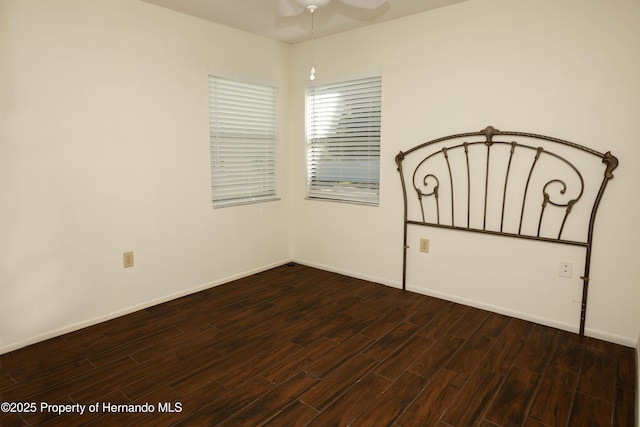 unfurnished bedroom featuring baseboards, ceiling fan, and dark wood-style floors