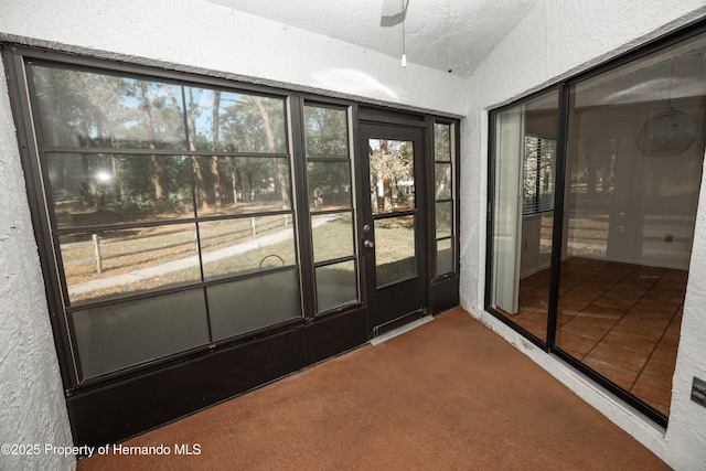 interior space featuring a textured wall, tile patterned flooring, ceiling fan, and carpet floors