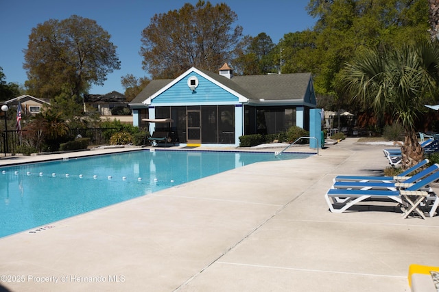 community pool featuring a patio, fence, and an outdoor structure