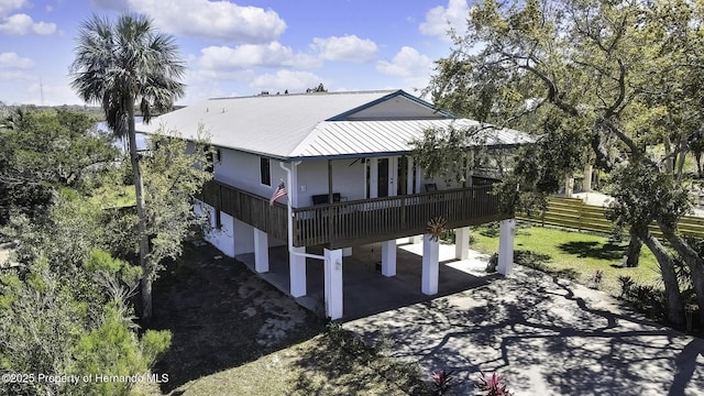 exterior space featuring concrete driveway, a carport, metal roof, and fence