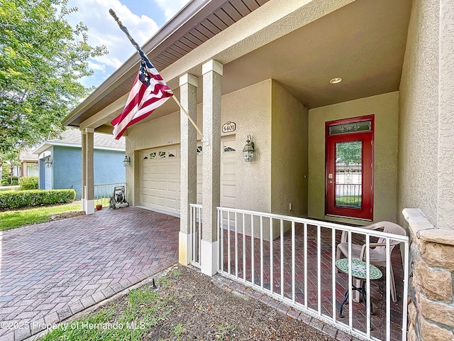 5401 Cappleman Loop, Brooksville, FL 34601 - doorway to property featuring stucco siding, a garage, and decorative driveway