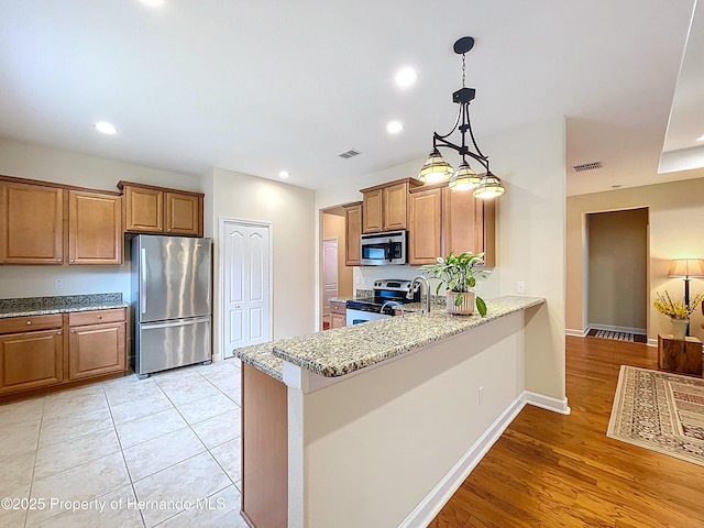 5401 Cappleman Loop, Brooksville, FL 34601 - kitchen with stainless steel appliances, light stone countertops, a peninsula, brown cabinetry, and recessed lighting