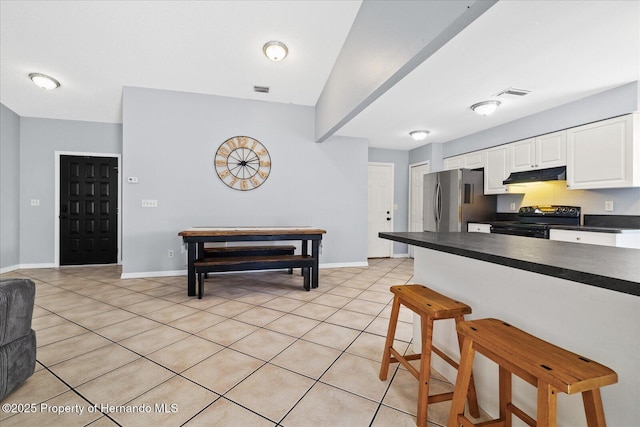 12575 Maleo Rd, Weeki Wachee, FL 34614 - kitchen with black electric range oven, freestanding refrigerator, under cabinet range hood, dark countertops, and a breakfast bar