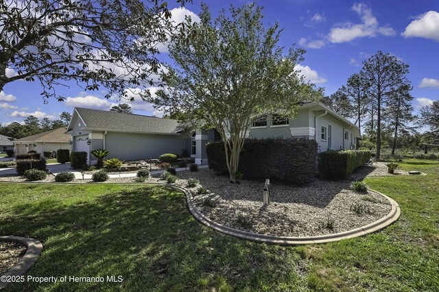 17364 Mediterranean Cir, Brooksville, FL 34614 - view of side of home featuring an attached garage, stucco siding, and a lawn