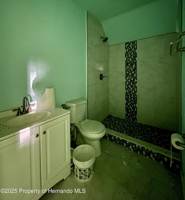 full bathroom featuring toilet, a tile shower, vanity, and vaulted ceiling