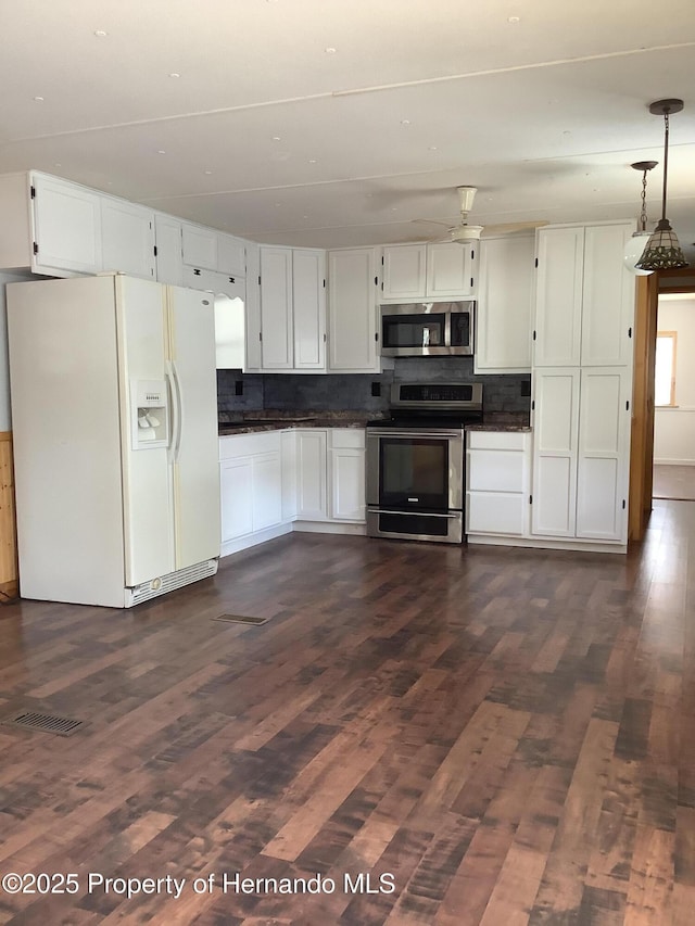 kitchen with appliances with stainless steel finishes, dark wood-style flooring, dark countertops, and backsplash