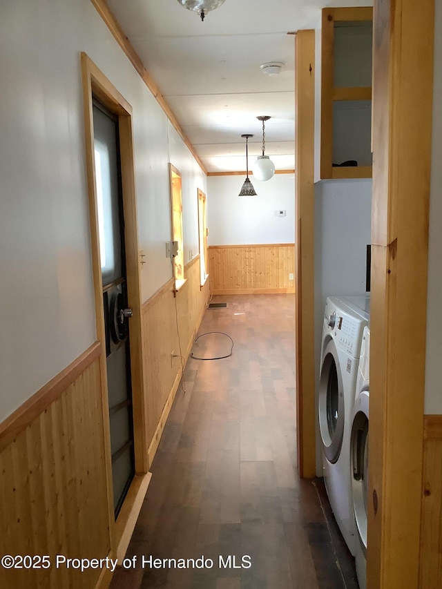 laundry room with laundry area, wood walls, wainscoting, tile patterned floors, and washing machine and dryer