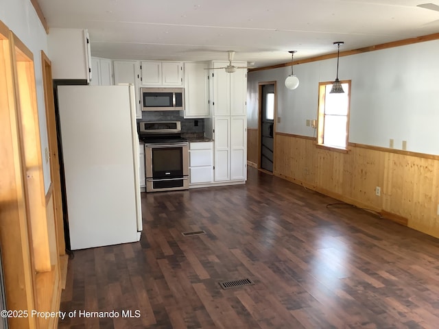 kitchen with stainless steel appliances, wainscoting, white cabinetry, and dark wood-style flooring