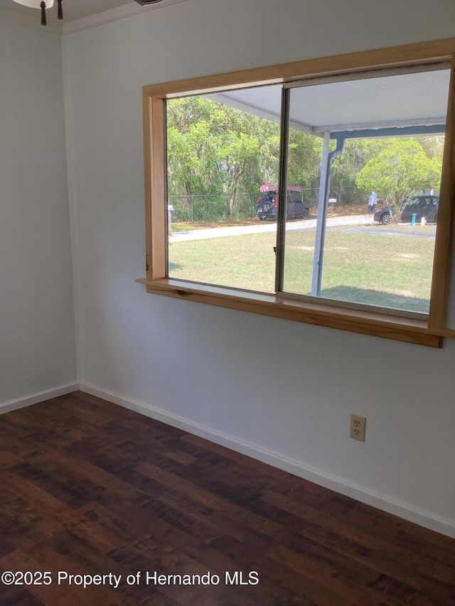 empty room with a wealth of natural light, baseboards, and dark wood finished floors