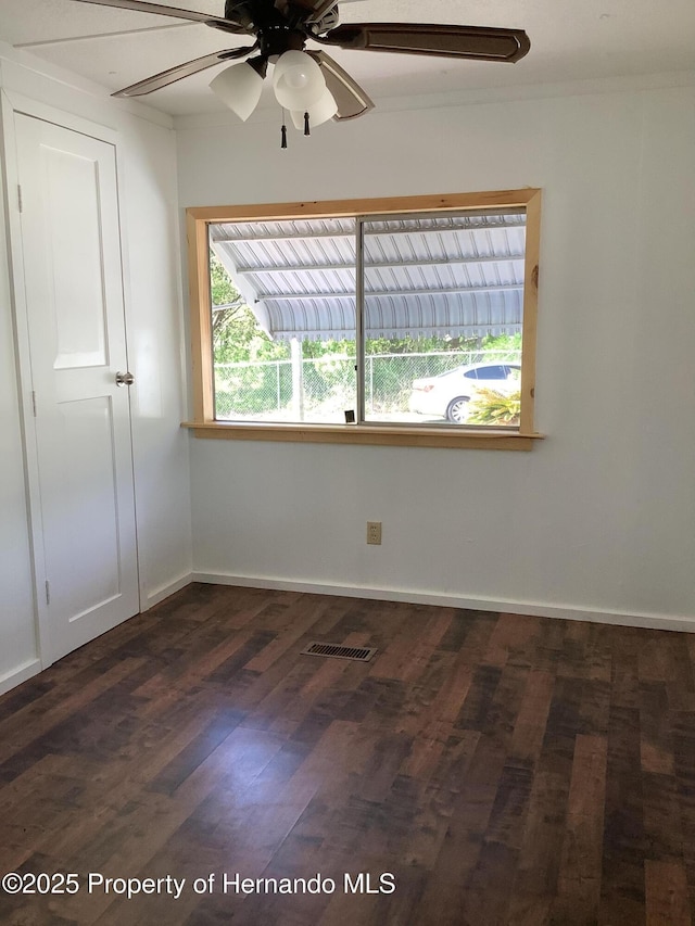 unfurnished room featuring visible vents, baseboards, a ceiling fan, and dark wood-style floors