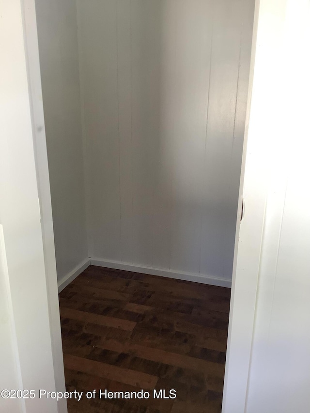 unfurnished room featuring baseboards and dark wood finished floors