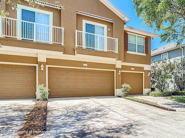 multi unit property featuring a garage, driveway, and stucco siding