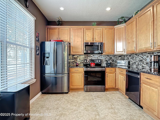 kitchen featuring baseboards, decorative backsplash, dark stone counters, and appliances with stainless steel finishes
