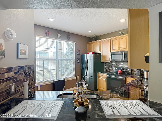 kitchen with a textured ceiling, light brown cabinets, decorative backsplash, and appliances with stainless steel finishes