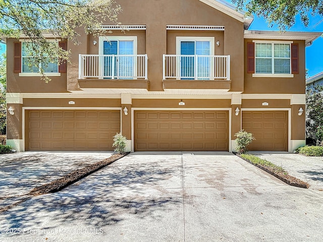 multi unit property featuring a garage, stucco siding, and concrete driveway
