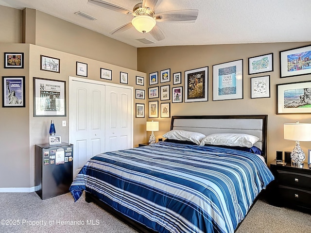 carpeted bedroom featuring ceiling fan, a textured ceiling, a closet, visible vents, and lofted ceiling