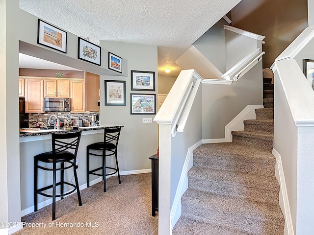 stairs featuring a textured ceiling, carpet flooring, and baseboards