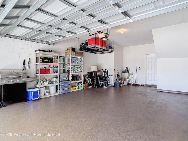 garage featuring a garage door opener and concrete block wall
