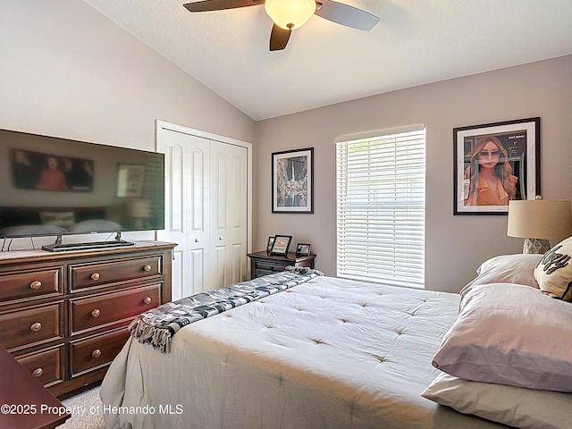 carpeted bedroom featuring a closet, a ceiling fan, and lofted ceiling