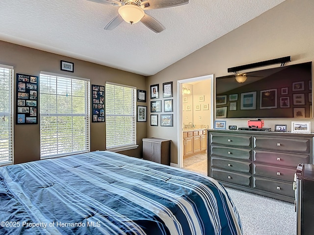 bedroom with light carpet, ensuite bath, a textured ceiling, a ceiling fan, and lofted ceiling