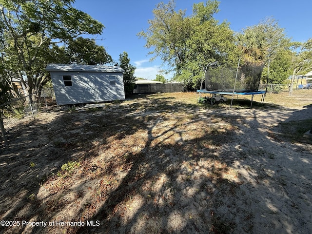 view of yard with an outbuilding, a fenced backyard, a trampoline, and a storage shed