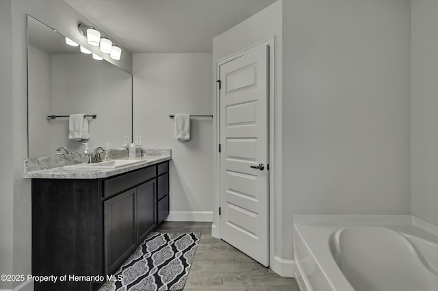 12848 Hilary St, Spring Hill, FL 34609 - full bathroom featuring a garden tub, vanity, baseboards, and wood finished floors