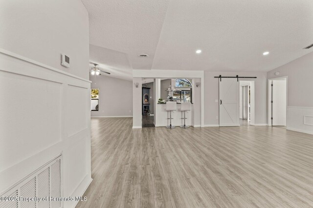 4405 Plumosa St, Spring Hill, FL 34607 - unfurnished living room featuring a barn door, recessed lighting, light wood-style floors, a textured ceiling, and ceiling fan