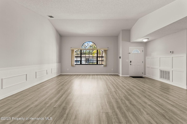 4405 Plumosa St, Spring Hill, FL 34607 - unfurnished living room featuring a wainscoted wall, wood finished floors, a textured ceiling, and visible vents