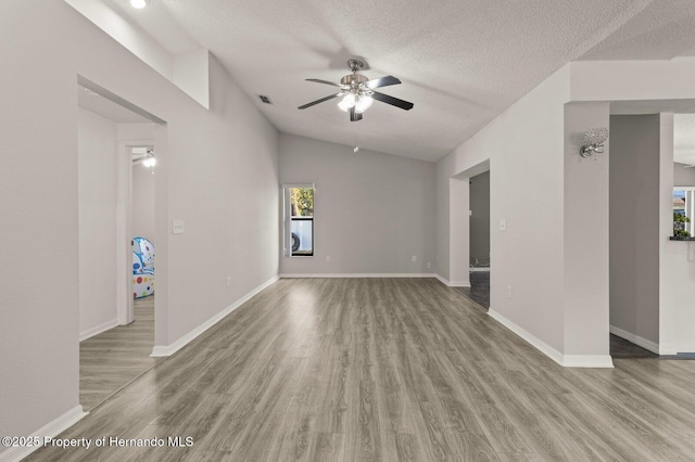 4405 Plumosa St, Spring Hill, FL 34607 - unfurnished living room featuring a ceiling fan, wood finished floors, a textured ceiling, baseboards, and lofted ceiling
