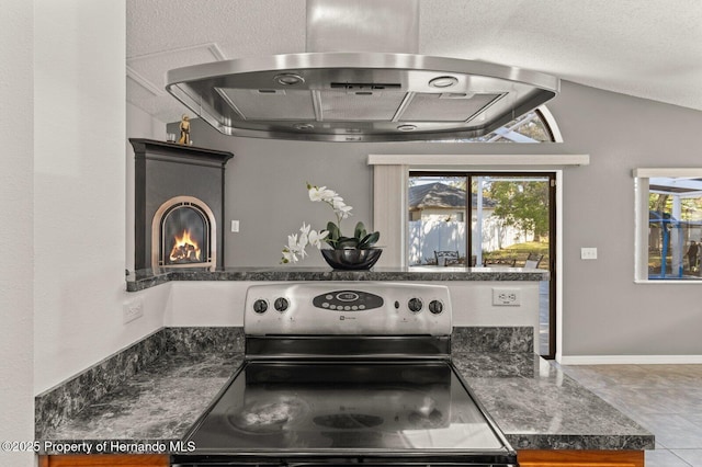 4405 Plumosa St, Spring Hill, FL 34607 - kitchen featuring a textured ceiling, dark countertops, a glass covered fireplace, range hood, and stainless steel range with electric stovetop