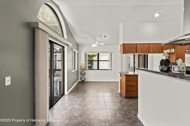 4405 Plumosa St, Spring Hill, FL 34607 - kitchen with a ceiling fan, a textured ceiling, brown cabinets, wall chimney exhaust hood, and dark tile patterned floors